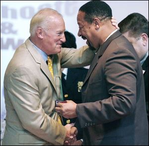Mayor Carty Finkbeiner congratulates Ray Wood, named Toledoan of the Year for business community investment, during the program at the Erie Street Market.
