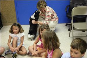 Toledo Area Humane Society spokesman Sherri Miller gets a loving smooch from friendly Cricket, an employee's dog, during the Forever Friends Learning Center's recent visit to the society, at 1920 Indianwood Circle in Maumee. 
