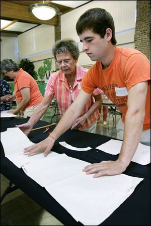 NBRW uniforms24p  07/17/ 2008 The Blade/Dave Zapotosky Caption: Donna Tallent of Westgate Chapel in Toledo, left, helps David McChesney of Gesu Church in Toledo, right, layout a paper pattern on a piece of fabric so he can cutout pieces of a uniform jumper at Sylvania United Church of Christ in Sylvania, Ohio, Thursday, July 17, 2008.  The skirt and jumper kits will be sewn together by volunteers at a late date and distributed to needy Toledo Public School students.  Summary: Volunteers will be packaging kits of school uniforms for low income kids from 9 a.m. to noon July 17 and 24. The uniforms are distributed by Project Dignity.