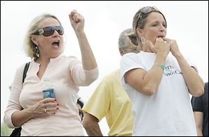 HCR Manor- Care Inc. employees Chris Darvas, left, and Robin Bowen cheer on their firm s boat as co-workers
board the 40- foot-long vessel to compete on the Maumee.