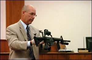 Keith Williamson, an investigator for the Ohio Bureau of Criminal Identification and Investigation, holds the Colt automatic weapon that Lima Sgt. Joe Chavalia used to shoot a woman and her son during a 'no-knock' police raid in January. 