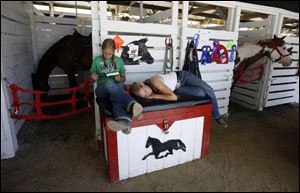 Twins Claire Kaisler, 18, of Tipton and her sister Maria Kaisler take some time to relax with their horse Winston, at the county fair.