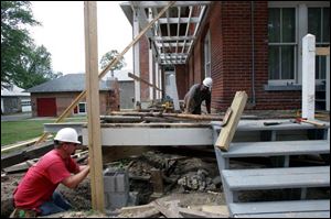 Lima craftsmen Chris Pack, left, and Chad Keiser, employees with Hume Supply, restore floor joists as part of a renovation project at the Wood County Historical Society and Museum.
The museum is spending $435,000 to replace the 100-year-old wrap-around porches on the former county home.