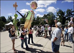 CTY artszoo11p  08/10/ 2008 The Blade/Dave Zapotosky Caption: Toledo School for the Arts students from left, Grace Roper, 14, Savannah Lough 14, and Melissa Ramirez, 15, entertain Donald ReVels of Toledo, right, with a giant puppet they made at school, during the Arts Gone Wild Event at the Toledo Zoo, Sunday, August 10, 2008. Summary: Arts Gone Wild at the Toledo Zoo.