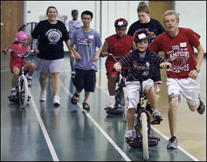 Jonathan Niese, 16, helps Steve Chirgott, 12, in the Lose the Training Wheels camp at the University of Toledo's Health Education Center. The engineer organizing the event used his knowledge of the mathematics of movement. 
