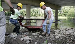 Findlay residents Brian Bibler, left, and Eric Stroub work for the National Emergency Grant Project clearing debris from the Blanchard River in Findlay. 

