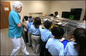Shirley Munoz replenishes the supply of hot dog buns for hungry Sherman first and second graders in the lunch line. The state lunch program gives those children
whose parents are on public assistance free or reduced meals without a lengthy application process, although
parents not on aid but whose income still qualifies for
meal help must fill out forms.
