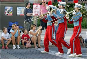 Oregon residents Henry Miller, 9, left, Elaine Miller, and Theodore Miller, 6, and Toledoan Theresa Brown cheer the Bowsher High School band.