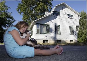 Maria Duran plays with Cougar in the front yard of her home, an apartment building she and her family share with four other low-income families. The pressure is on for them to move before their 30-day time frame is up because the city of Sylvania says the site is important for its gateway corridor project. The purchase agreement requires the buildings be empty at the time of the sale. 