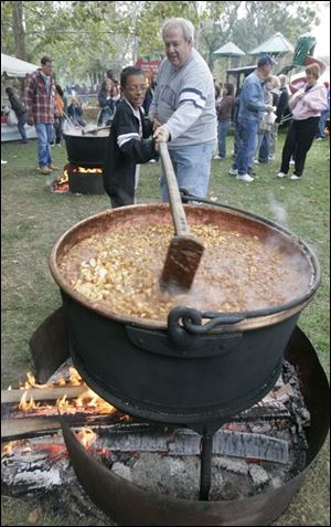 Gregary Brunner of Berlin Center, Ohio, left, helps Jack Jones of Bowling Green, stir a pot of apple butter during last year's Applebutter Fest in Grand Rapids, Ohio.