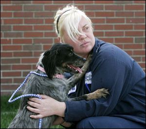 Jodi Duff, an employee of the Lucas County Dog Warden, holds a mixed 2-year-old female dog that's available for adoption. They were at a news conference where county government officials and local animal groups pledged to work together in an effort to increase the rate of adoptions from the county's dog pound by 10 percent next year. Skeldon