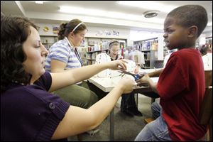 Slug: NBRN music13p Date:  11/04/2008        The Blade/Andy Morrison       Location:   Monroe  Caption: Branch librarian Amber Reed helps Daniel Robertson and other children make shekeres, a Nigerian instrument, as part of Musical Instruments Around the World program at L.S. Navarre Library Branch in Monroe, Wednesday, 11/05/2008. Summary: