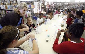 Slug: NBRN music13p Date:  11/04/2008        The Blade/Andy Morrison       Location:   Monroe  Caption:  Kelli Strimbel, Dundee Branch children's librarian, helps children make shekeres, a Nigerian instrument, as part of Musical Instruments Around the World program at L.S. Navarre Library Branch in Monroe, Wednesday, 11/05/2008. Summary: