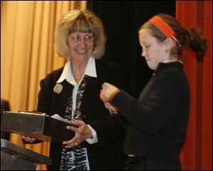 Principal Gretchen Bueter, left, holds the time capsule so Madeline Lockyer can photograph its contents.