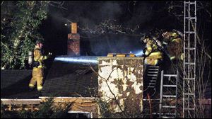 Sylvania Township firefighters pour water on the smouldering remains of a home at 2523 North Centennial Rd., where 2 women died and  and man and another woman were injured seriously. 