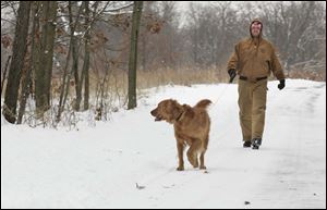 Don Carey of Toledo takes his dog, Andy, for a walk in snow-covered Wildwood Preserve Metropark. More snow is forecast tonight. 
