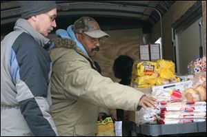 Mitch Magdich, left, assists James Cranon at the Food for Thought trailer outside the Aurora Gonzalez Community Center. Mr. Cranon foresees a growing need for such programs.