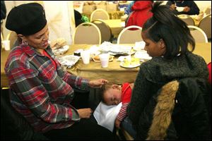 Tonya Badgett, left, watches her grandson Jeremiah Badgett sleep on his mother Jayvia's lap after their meal at Thomas Temple.