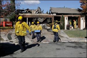 Firemen carry some of their equipment from the residence where a gunman dressed as Santa Claus killed nine people Wednesday night before killing himself.
