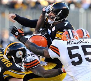 Ben Roethlisberger is driven to the ground by Willie McGinest, right, and D'Qwell Jackson. He left the game after the play.