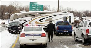 A pickup pulling a recreational vehicle ends up sideways blocking icy southbound lanes of I-75 at Phillips Avenue Saturday.