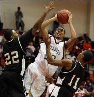 Scott guard Vernon Freeman drives to the hoop between Akron Buchtel defenders Steve Hargrove (22) and Tajh Dent (11).