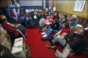 Edward Dixon, sitting on the floor at right, hosts a gathering in his Old West End home for friends and relatives to watch the inauguration of the nation's first black president. 