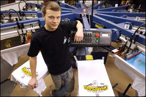 Aveey Lucas stands next to a press at Image Group in Springfield Township that is set up with two designs for children's T-shirts.