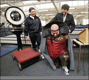Andrew Zepeda's tailor made the robes that County Commissioner Ben Konop removes as Robert Alexander of the YMCA, left, watches.