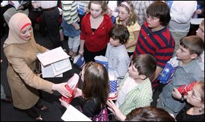 Leyla Orra, formerly of Lebanon, gets a present from New Riegel School fifth graders, at right, after taking the oath of citizenship during ceremonies held Friday at Clay High School in Oregon.