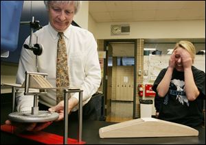 Junior Ciera Ward can barely watch while professional engineer Stuart C. Salmon prepares to put a weight on her balsa-wood bridge to test it at Notre Dame Academy. Students in Mr. Salmon s engineering class were given a limited amount of balsa with which to design and build a bridge no more than 19 inches long and three inches high. Mr. Salmon then made sure yesterday that they would hold 10 pounds. Notre Dame has added the engineering class to its curriculum because it s a high-demand career, and women currently comprise only about 11 percent of the nation s engineers.
