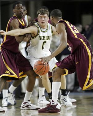 Michigan guard Zack Novak slips between Minnesota forwards Paul Carter, left, and Damian Johnson in the first half last night in Ann Arbor.
