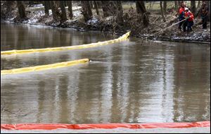 Workers from Clean Harbors Environmental Services use booms to contain crude oil that leaked into the Portage River earlier this week. An estimated 650 barrels were recovered.