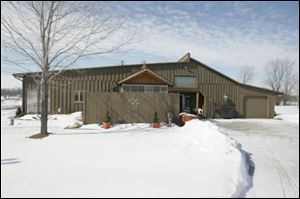 The former showroom's side is the home's main entrance. A garden and seating area is behind the fence.