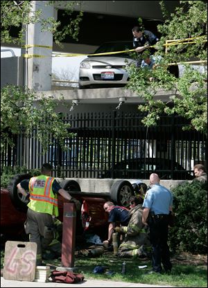 CTY  garage28p 04/27/09  The Blade/Dave Zapotosky Caption: Toledo police and  fire officials investigate the scene after a car drove off of the parking garage at St. Vincent Mercy Medical Center, in Toledo, Ohio, Monday, April 27, 2009.  There was one female occupant who was taken from the vehicle. Summary: Car drives off of the parking garage at St. Vincent Mercy Medical Center.