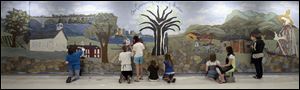 Volunteers paint scenes from here and from Lesotho, Africa, on a community mural that fits the length of a cafeteria wall.