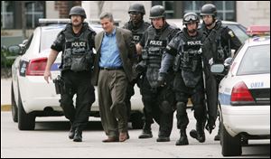 The suspect, Michael Swiergosz, is led away in handcuffs after hours of negotiations with Toledo police officers.