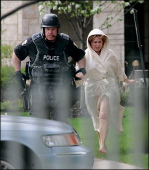 Barbara Swiergosz runs with an offi cer of the police SWAT team after being released as a hostage at The Woodlands apartments, part of the Sunset House complex on Indian Road.