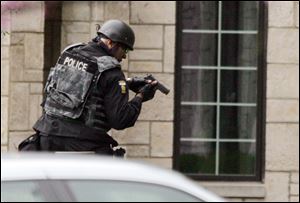 A Toledo police officer prepares himself moments before other offi cers bring out the suspect, Michael
Swiergosz. He faces multiple felonious assault and kidnapping charges.