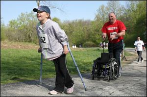 Abby Gase of Bowling Green has her eyes on the finish line as her father, Bill Gase, follows with her wheelchair during the fund-raiser at Swan Creek.