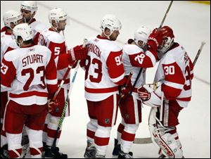 Detroit Red Wings goalie Chris Osgood receives congratultions from his teammates at the end of Game 4.