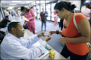 Walden Wilson from Lucas County Jobs and Family Services agency hands Jenica Brady vouchers that will allow her to attend a free Toledo Mud Hens game.