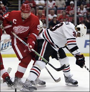 Detroit s Nicklas Lidstrom, left, and Chicago s Dustin Byfuglien chase the punk during the first period of their playoff game.