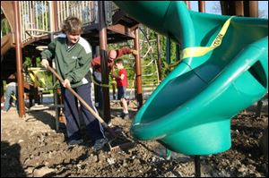 Carol Kutcher rakes the ground before mulch is put on the new playground at OLPH.