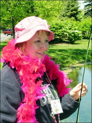 Pam Ackley Flowers of West Liberty, Ohio, wears a pink boa, an honor accorded Reeling and Healing participants for catching their first trout on a flyrod. Patti Schebil of LaSalle, Mich., takes a good look at her first trout taken on a flyrod.