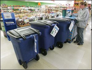 Toledoan Rose Wilson looks at trash containers at Toledo Food Center. The receptacles will be used to automate collection.
