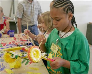 Rebekah Koster, 7, left, and Gabriel Dudley, 11, paint robotic cars at Clay High School. The youths were among 21 children aged 7 to 12 to participate in the school s robot wars program.