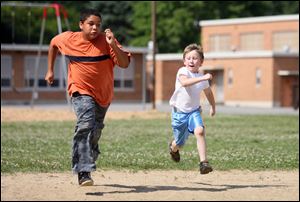 Slug: ROV ballwithmom                 Date 6/27/2009           The Blade/ Amy E. Voigt              Location: Toledo, Ohio  CAPTION:  Justin Krieg (cq), right, and Andrew Malone, left, from Toledo, race on the diamond at Monac Elementary School on June 27, 2009.