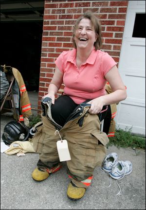 Trustee DeeDee Liedel pulls on her gear. There has been heat between her and the department, but, she said, she had just wanted to control costs.