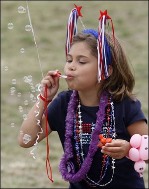 Dressed to celebrate, Alexis Hugo, 7, of Detroit blows bubbles at Promenade Park.
